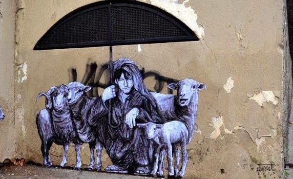Graffiit showing shepherd covering sheep with umbrella